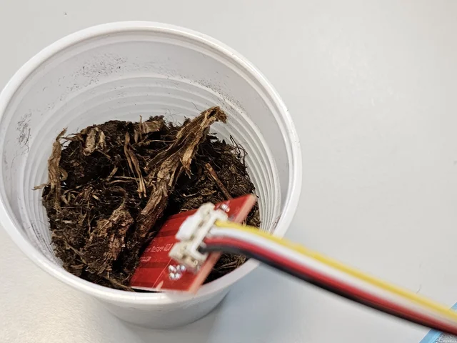 Sonda capacitiva de humedad del suelo clavada en un vaso con tierra y conectada al P-Bit